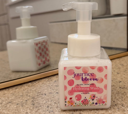Bottle of 'journee bloom' hydrating wash on a bathroom counter with a mirror in the background.