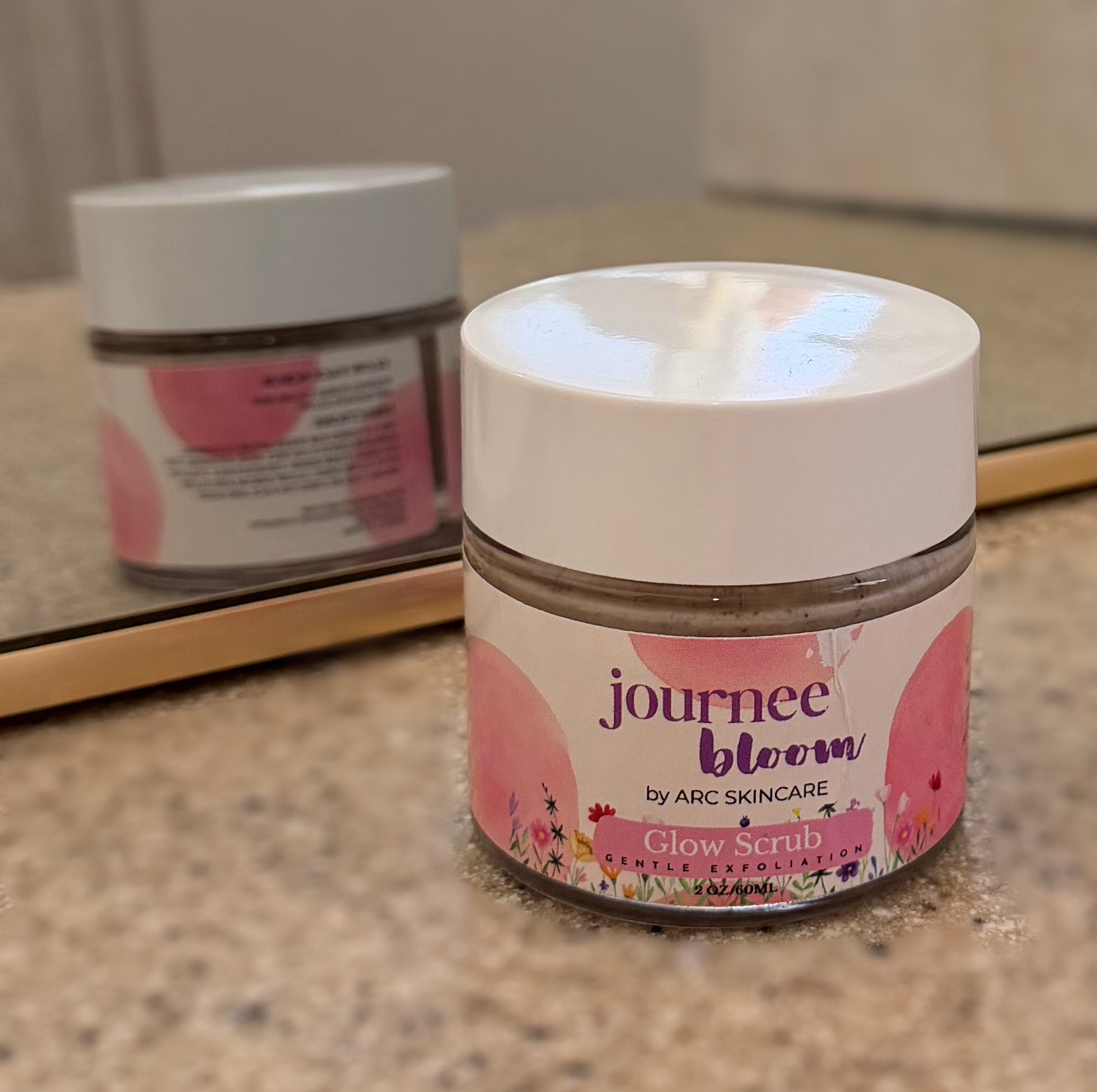 Jar of journee bloom Glow Scrub on a bathroom counter