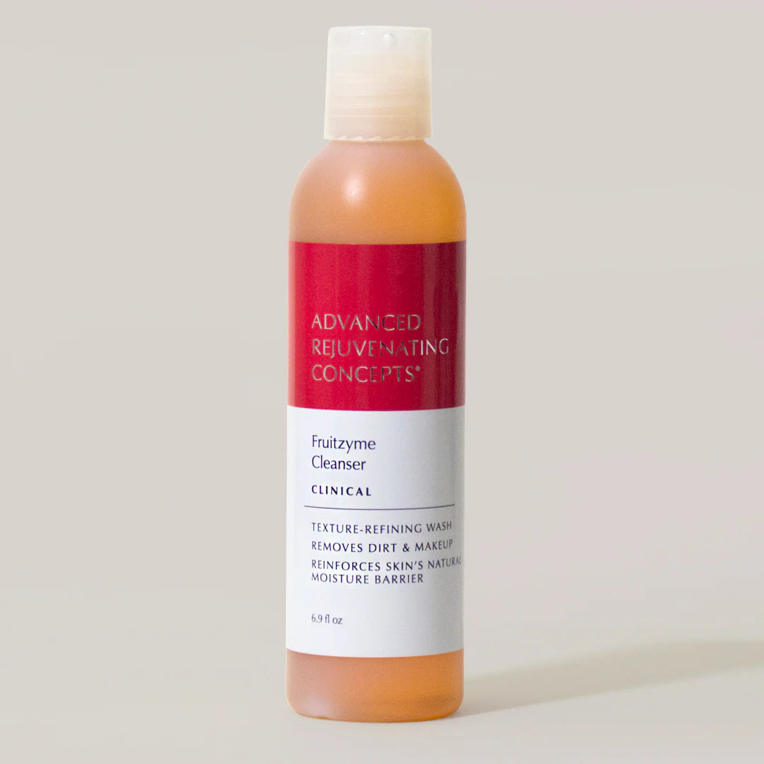 Fruitzyme Cleanser in a clear bottle with a red label, designed to remove dirt and makeup while refining skin texture.